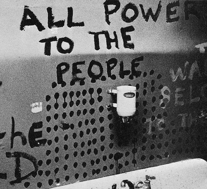 Image of a bathroom sink with the words 'All power to the people' painted above it